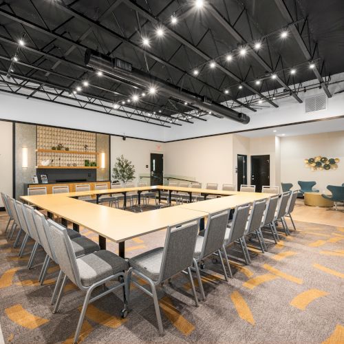 A modern conference room with a U-shaped table arrangement, chairs, and decorative plants creates a sleek and inviting atmosphere.