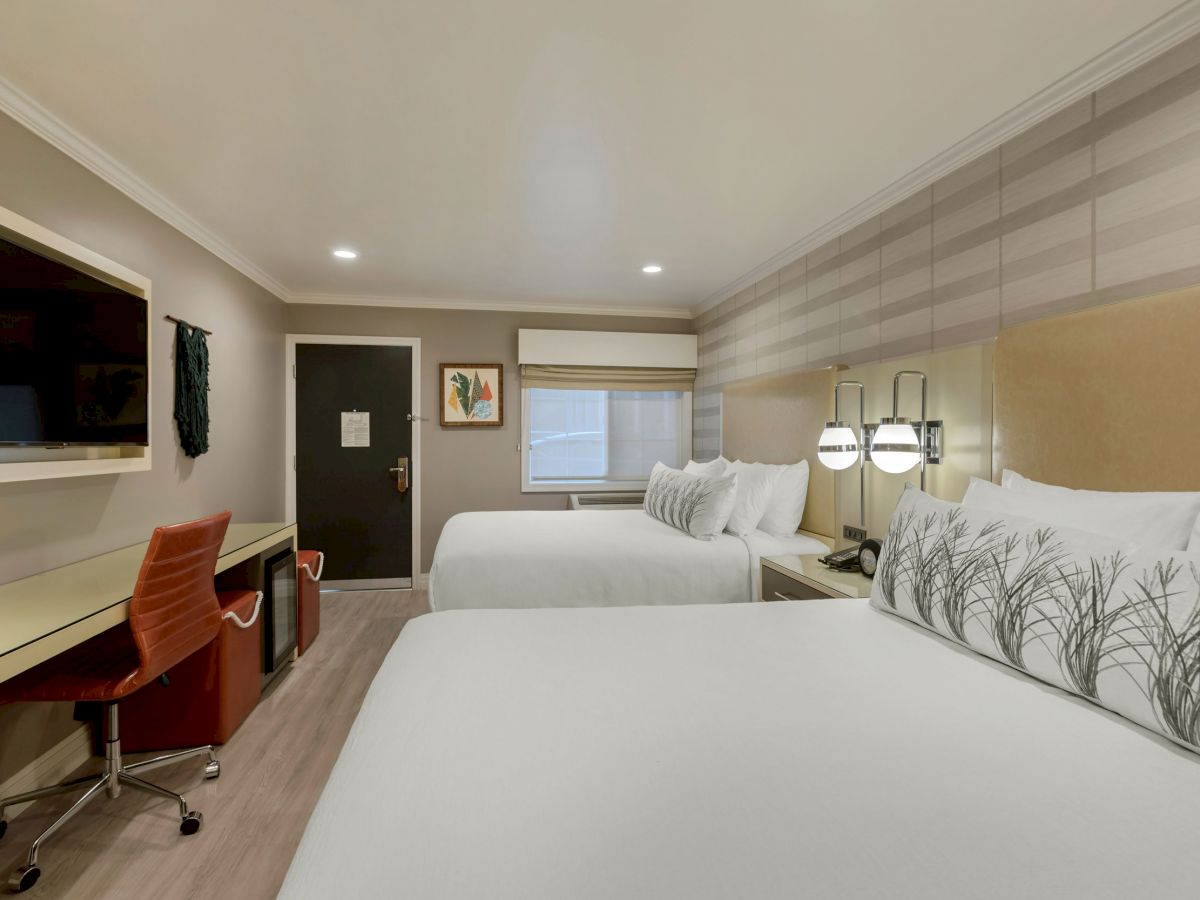 A modern hotel room features two neatly made beds, a flat-screen TV, a desk with an orange chair, and minimalistic decor.