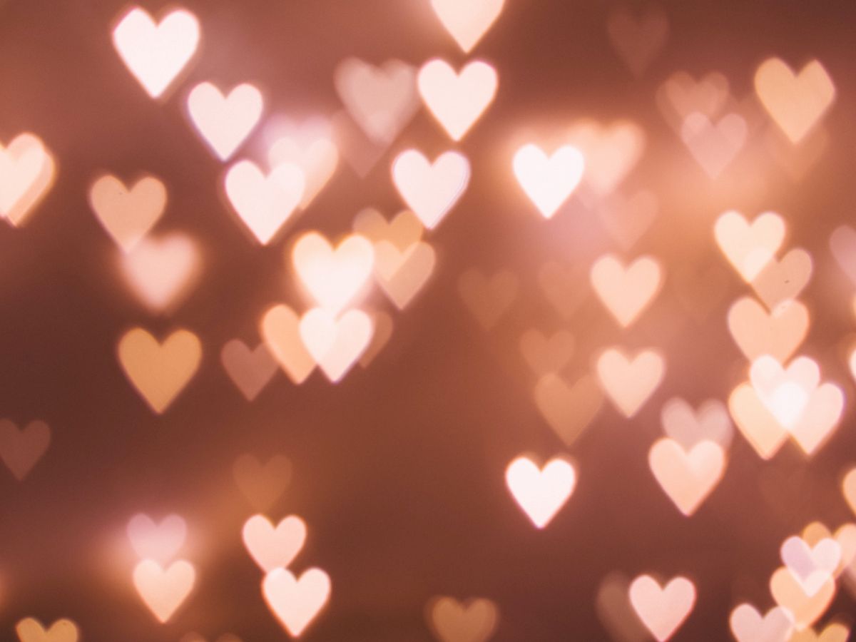 The image shows a blurred background with various soft heart-shaped lights glowing in warm tones of pink and peach, creating a romantic ambiance.