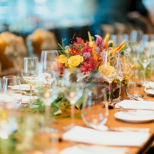 A beautifully set, elegant table with glassware, plates, cutlery, and a vibrant floral centerpiece, ready for a formal gathering or event.