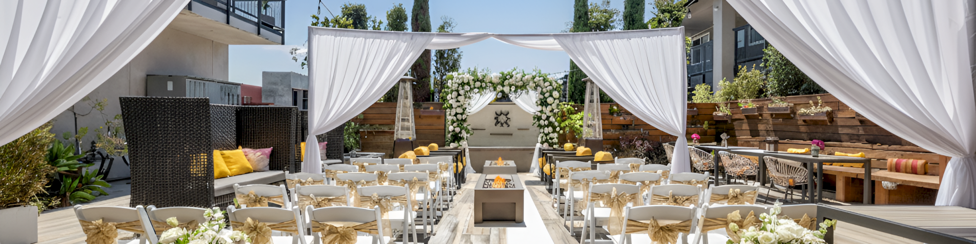 The image shows an outdoor wedding setup with chairs arranged in rows on a wooden deck, under a clear sky with string lights above.